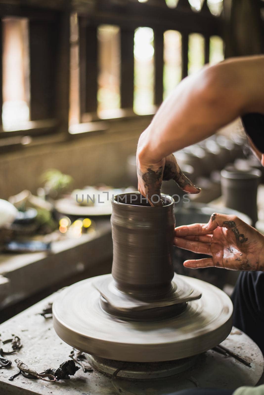 Closeup potter's hands shaping soft clay to make an earthen pot