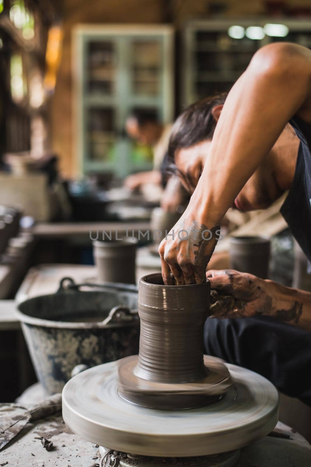 Closeup potter's hands shaping soft clay to make an earthen pot