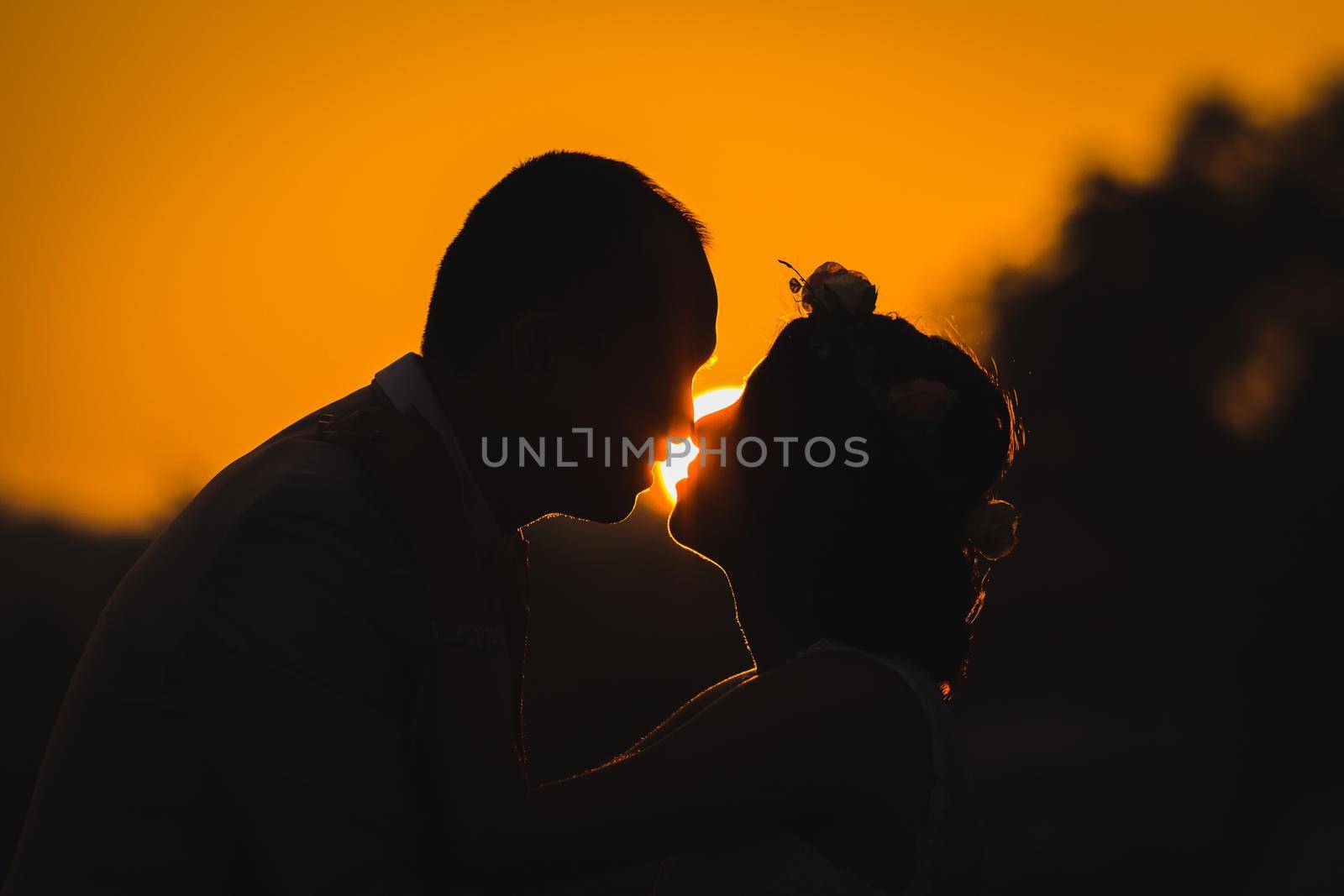 Romantic lovers hugging at silhouette with sunset