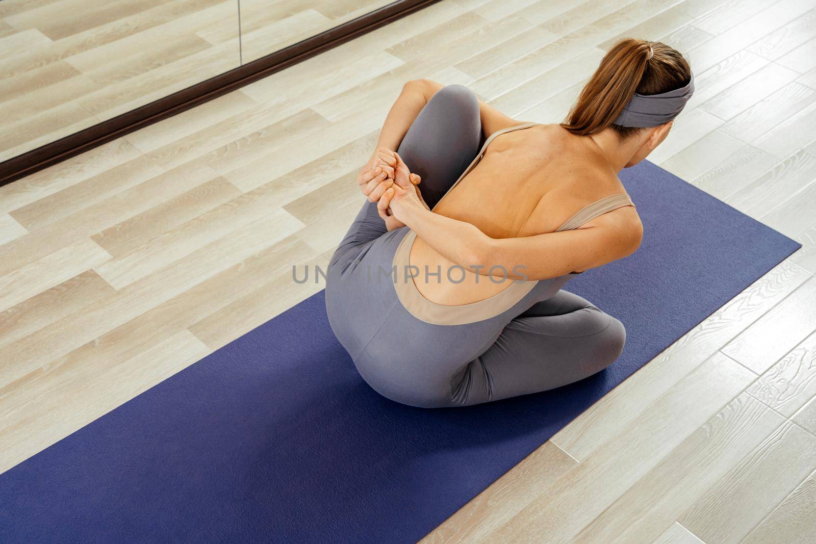 Young pretty girl doing yoga pose in, woman practicing yoga indoor by Mariakray