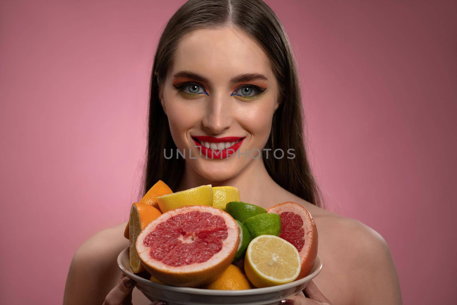 Fruit salad for cosmetic mask for girl face with natural make up and bare shoulders. Healthy pure skin model isolated on black background. Natural make up, spa and beautiful concept by LipikStockMedia