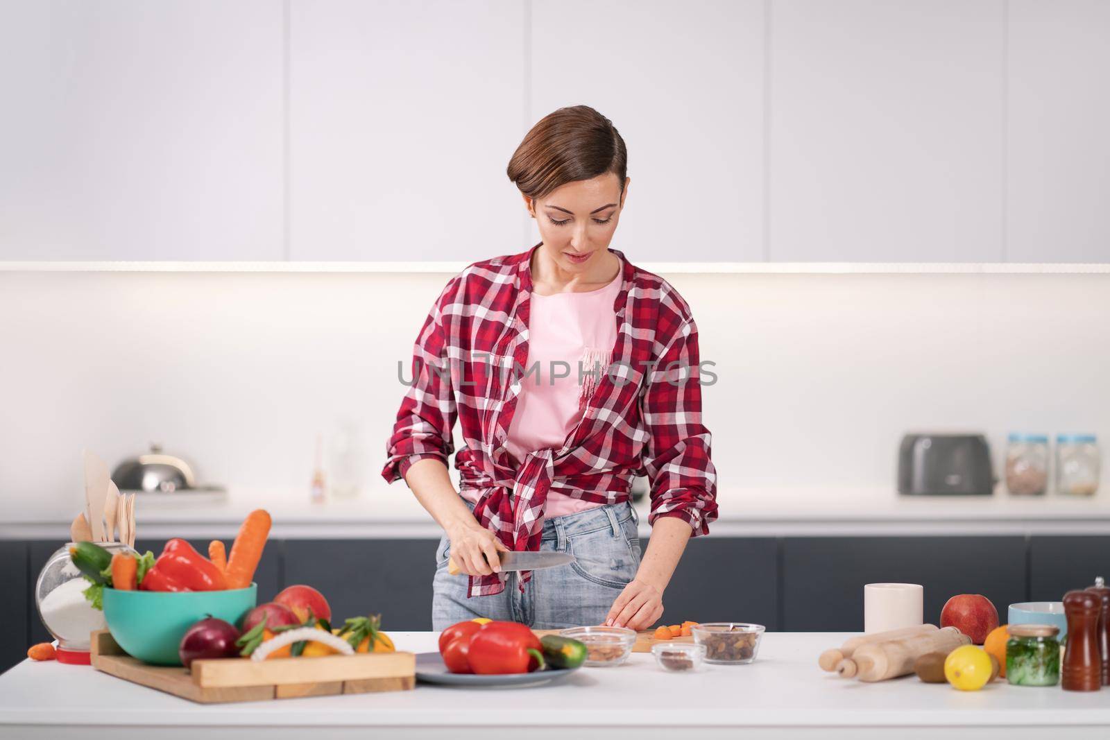 Cooking at new home for loving family. Preparing ingredients on table young woman cooking a lunch standing in the kitchen. Healthy food living. Healthy lifestyle. New home concept by LipikStockMedia