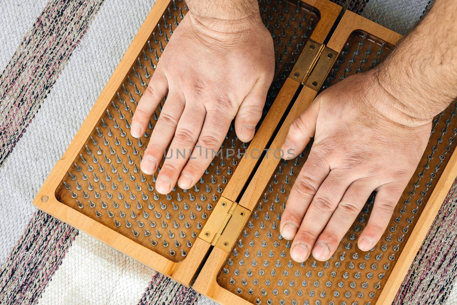 Man touching yoga wooden sadhu board with sharp nails by Mariakray
