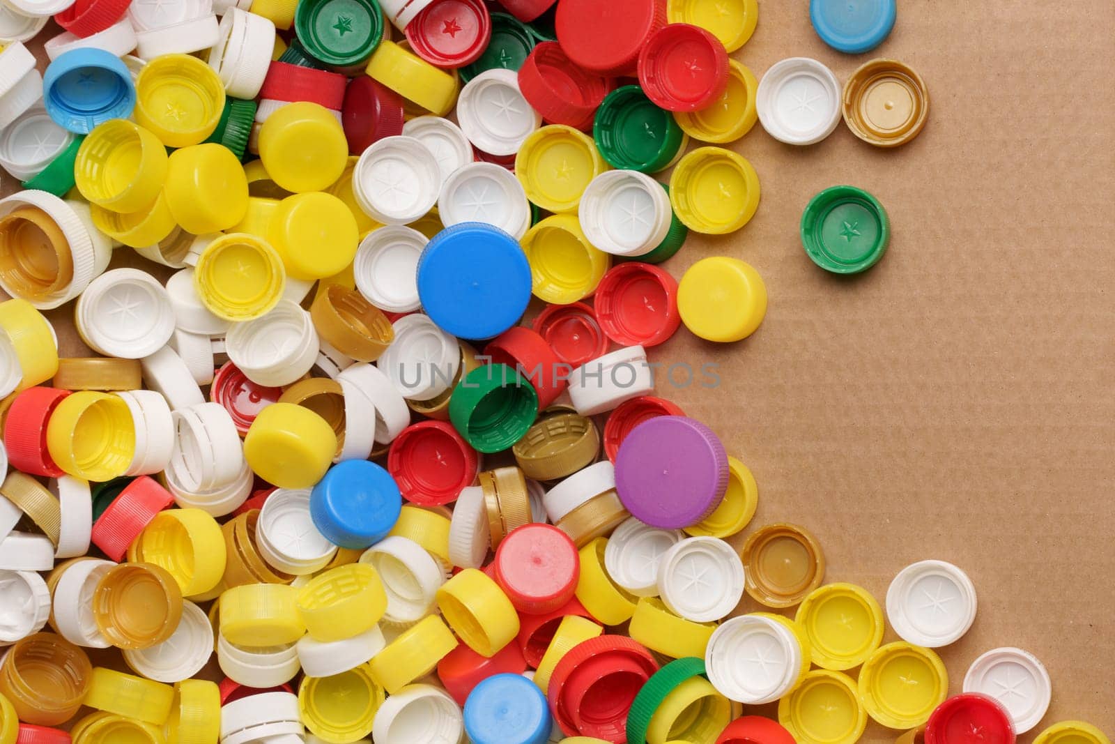 Used PET recycling plastic bottle cap plastic lids. Colorful bottle caps background cardboard box. Garbage PET waste recycling bottle cap sorting waste plastic garbage collection. Recyclable materials