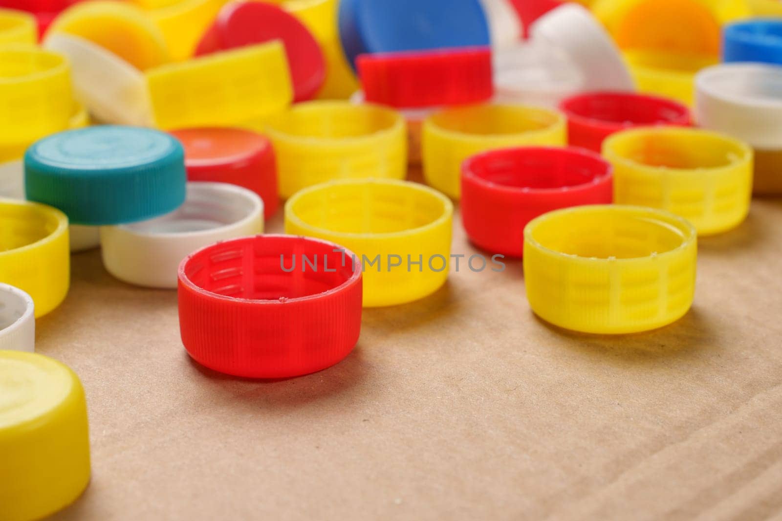 Colorful bottle caps background cardboard box. Used PET recycling plastic bottle cap plastic lids. Garbage PET waste recycling bottle cap sorting waste plastic garbage collection. Recyclable materials by synel