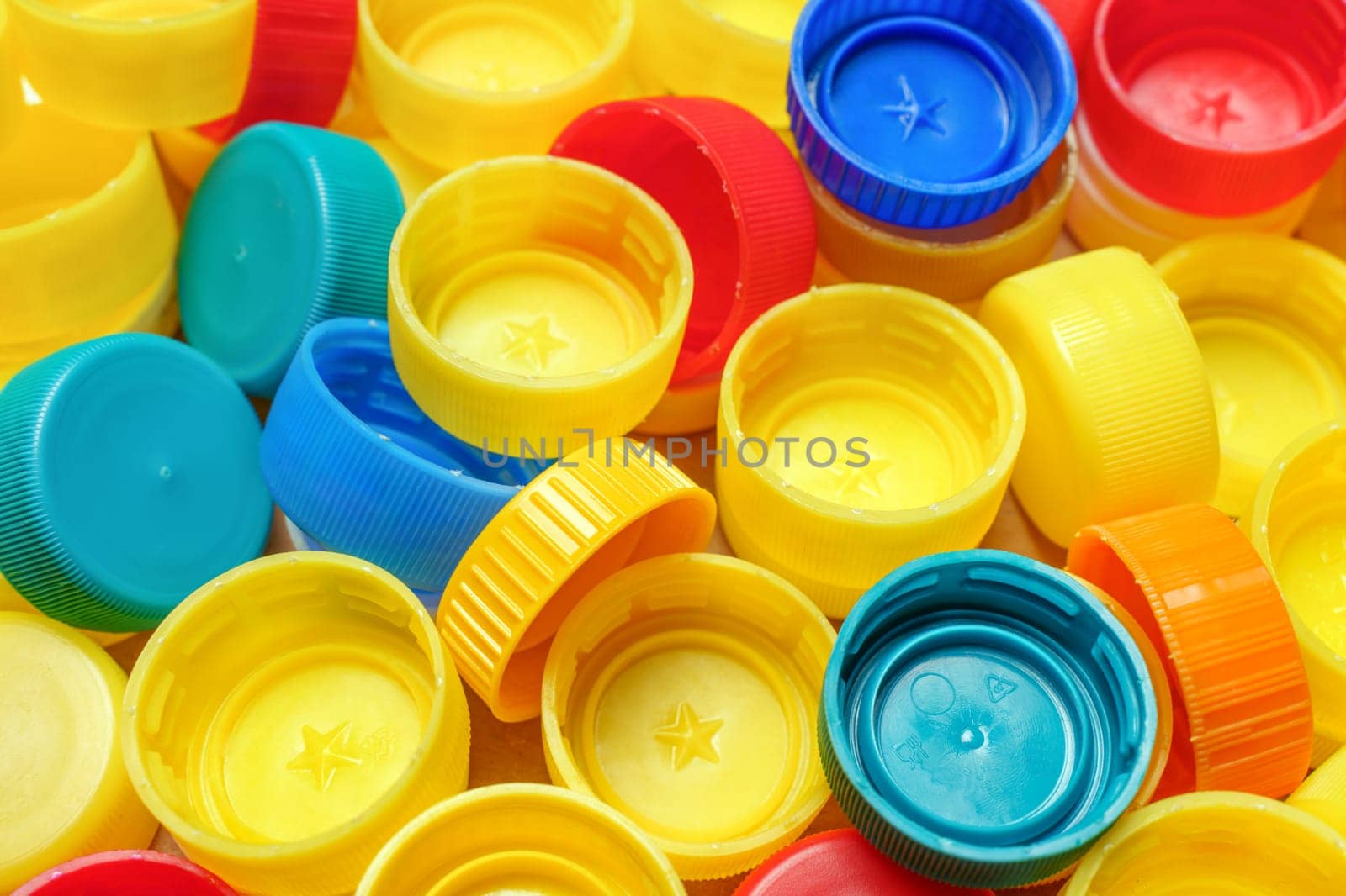 Pile of colorful bottle caps background. Used PET recycling plastic bottle cap plastic lids. Garbage PET waste recycling bottle cap sorting waste plastic garbage collection trash. Recyclable materials by synel