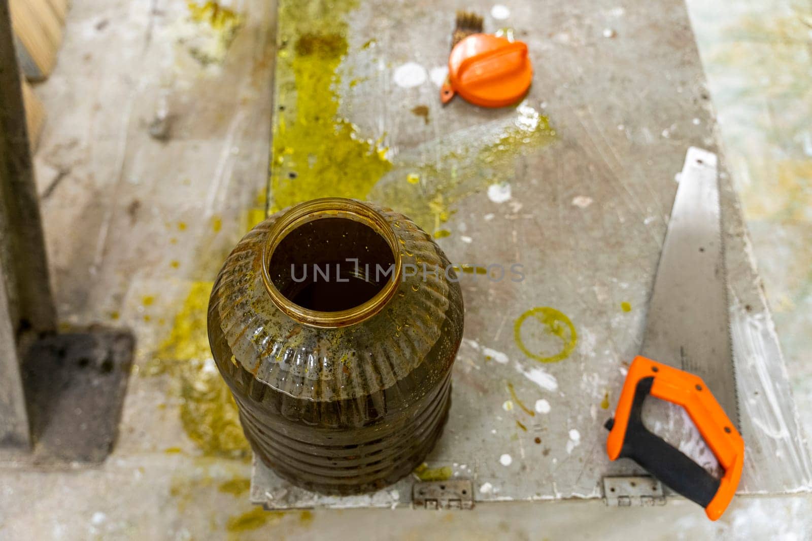 A jar with antiseptic impregnation for wood and a hacksaw. Sawing and Painting of wooden boards with special protective oil.Protection of wooden surfaces from bad weather and mold.