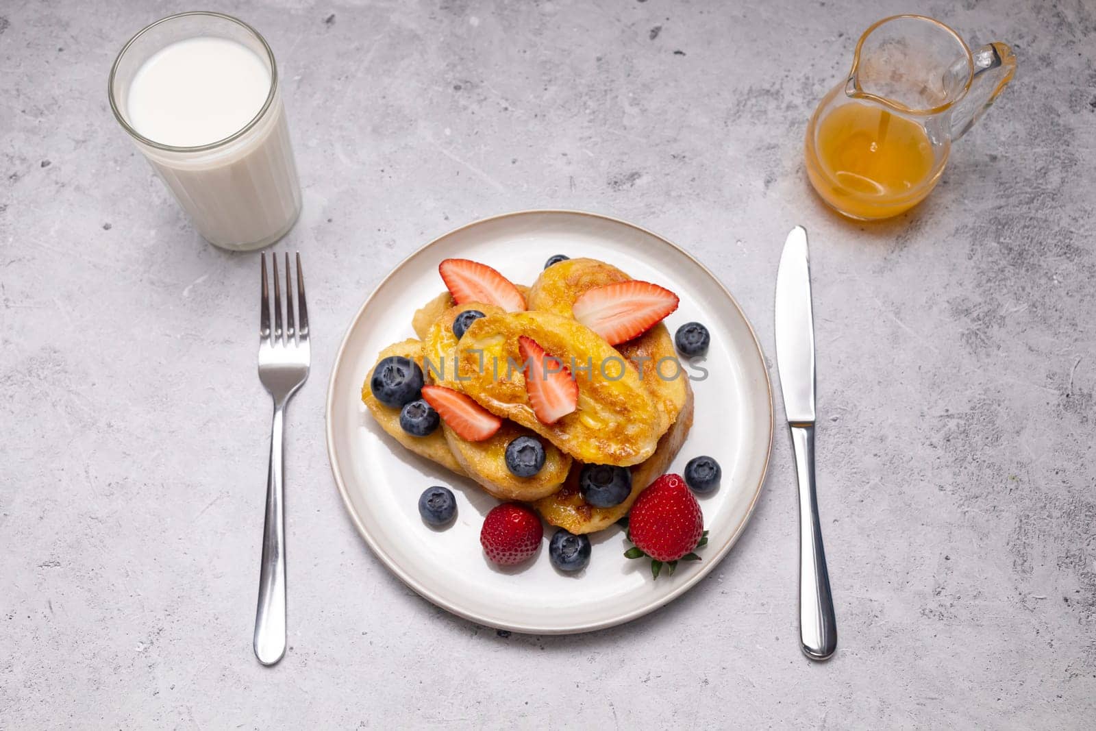 Torrijas, Spanish Style French Toast Served With Orange Topping, Glaze, Fresh Blueberries, Strawberry On Green Plate, Wooden Table. A Half Of Orange. Spanish Dessert. Horizontal plane.
