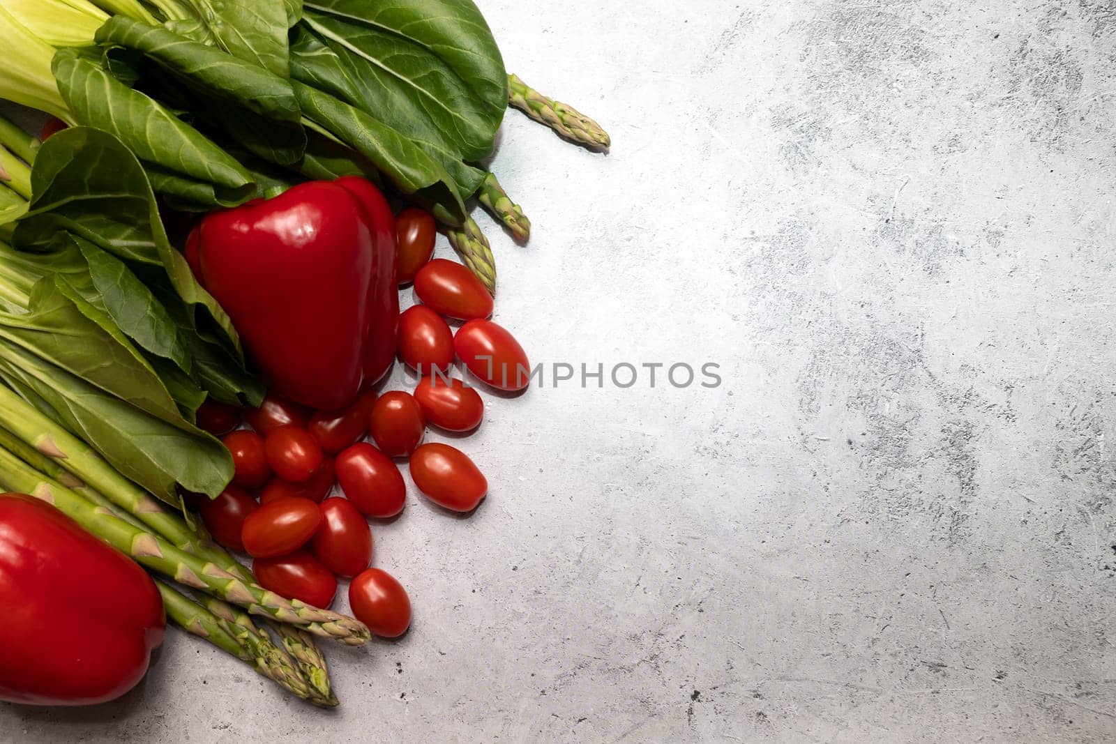 Mockup Assortment Of Fresh Organic Home Grown Red Green Vegetables On Gray Granite Table. Asparagus Plant, Bell Pepper, Bok Choy, Red Leaf Lettuce, Cherry Tomatoes. Flat lay. Horizontal, copy space