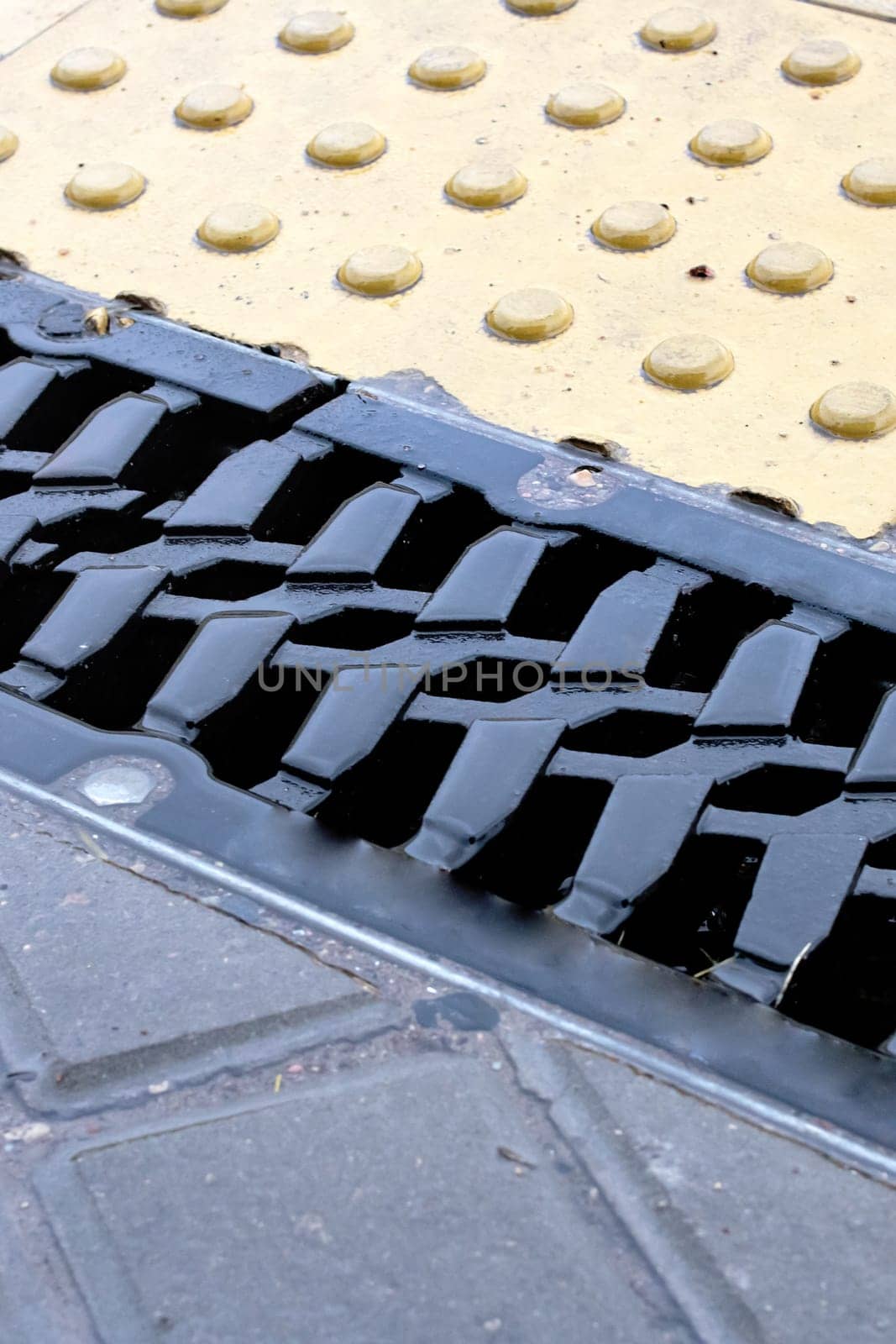 Rain grate on the sidewalk in the rain by Vera1703