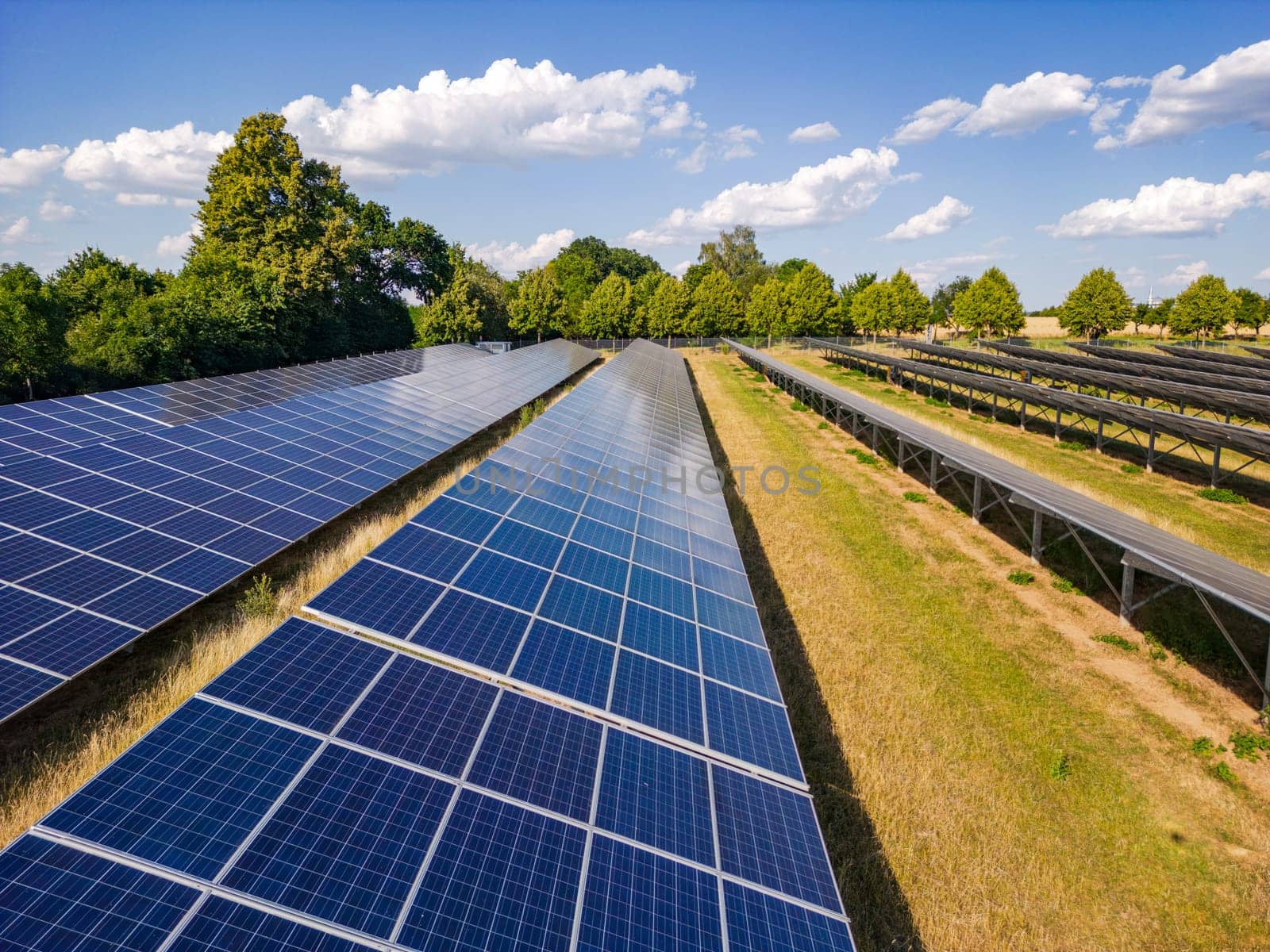 Solar panels of an open space installation with photovoltaic modules on an agricultural field on a day with sunshine, drone perspective, Germany