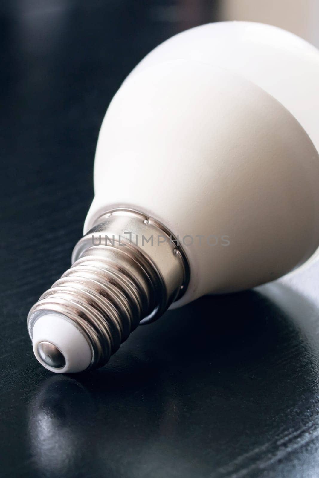 Light bulb base on black wooden table, copy space