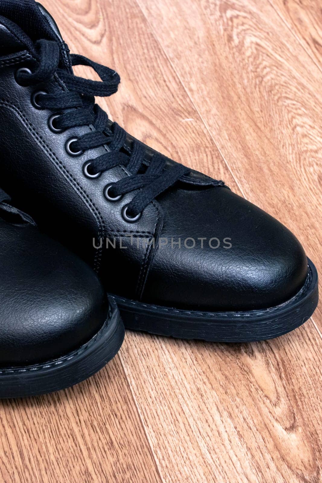 Black leather mens boots on wooden floor close up