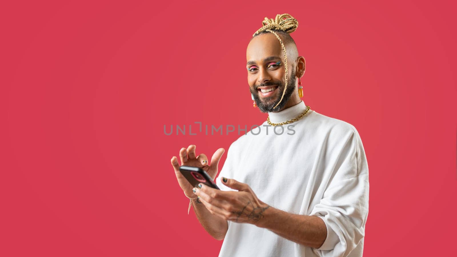 Trendy black latin gay man in white clothes use smartphone looking at camera on pink background studio portrait People lifestyle fashion lgbtq concept