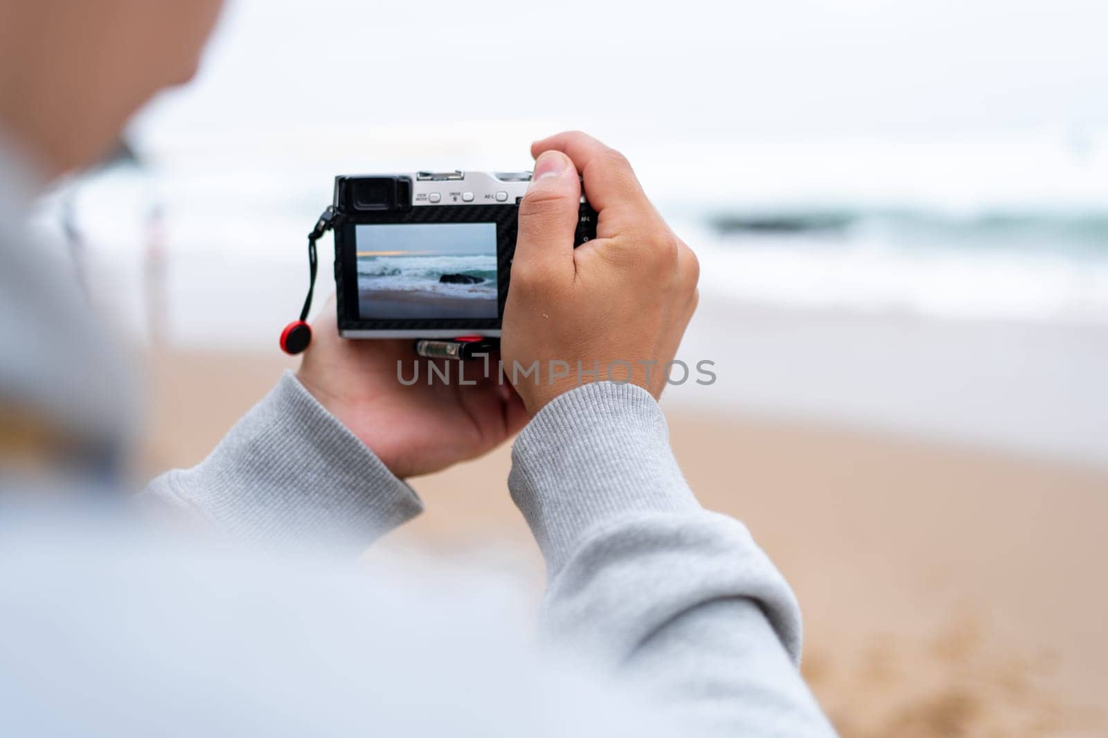 Traveller make photo using mirrorless camera in hand, travel blogger, Close up of mens hands holding mirrorless camera taking picture at ocean view