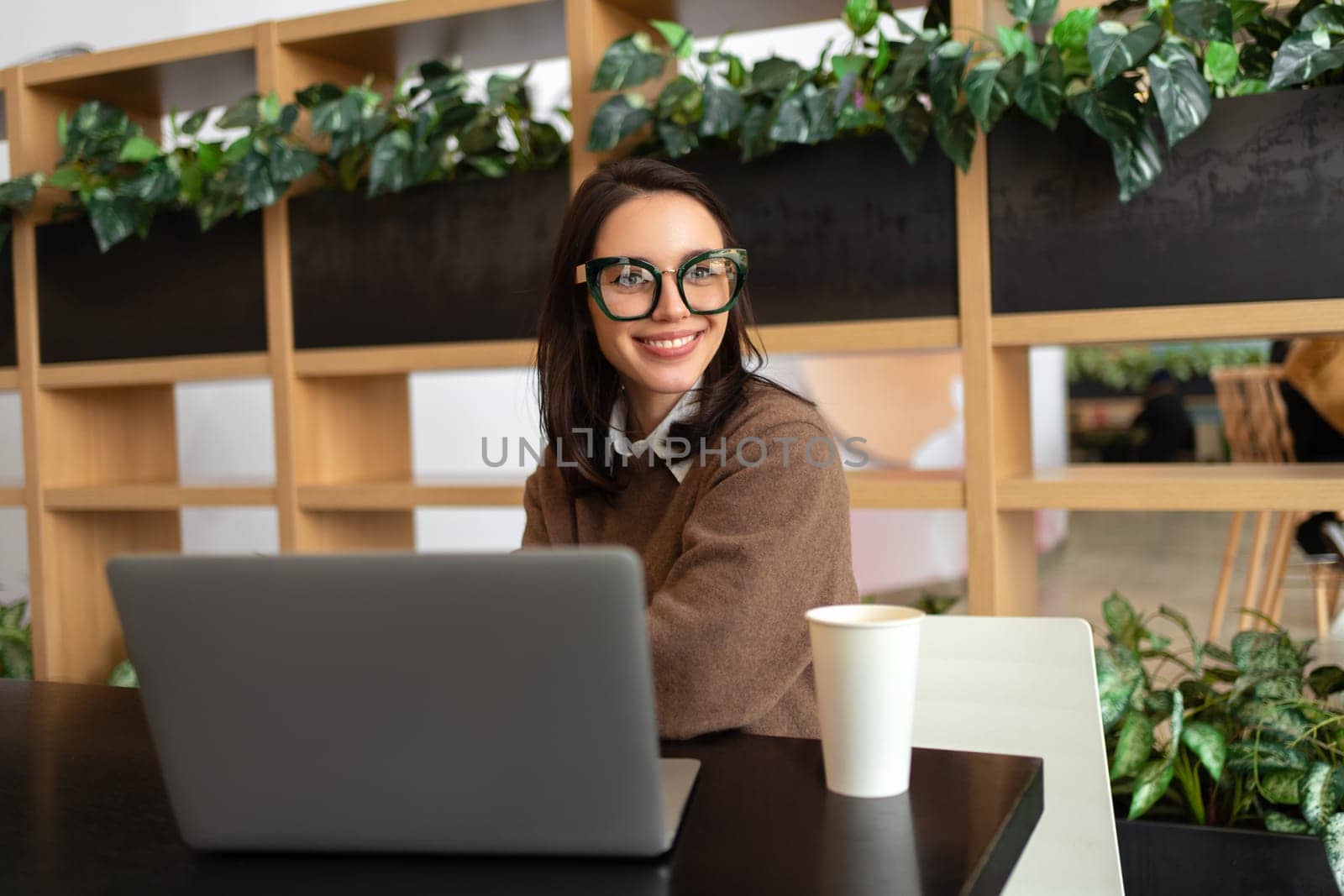Woman Wearing Glasses using Laptop. Smiling businesswoman in eyeglasses and casual clothes working with laptop computer watching side. Elegant business female medium shoot