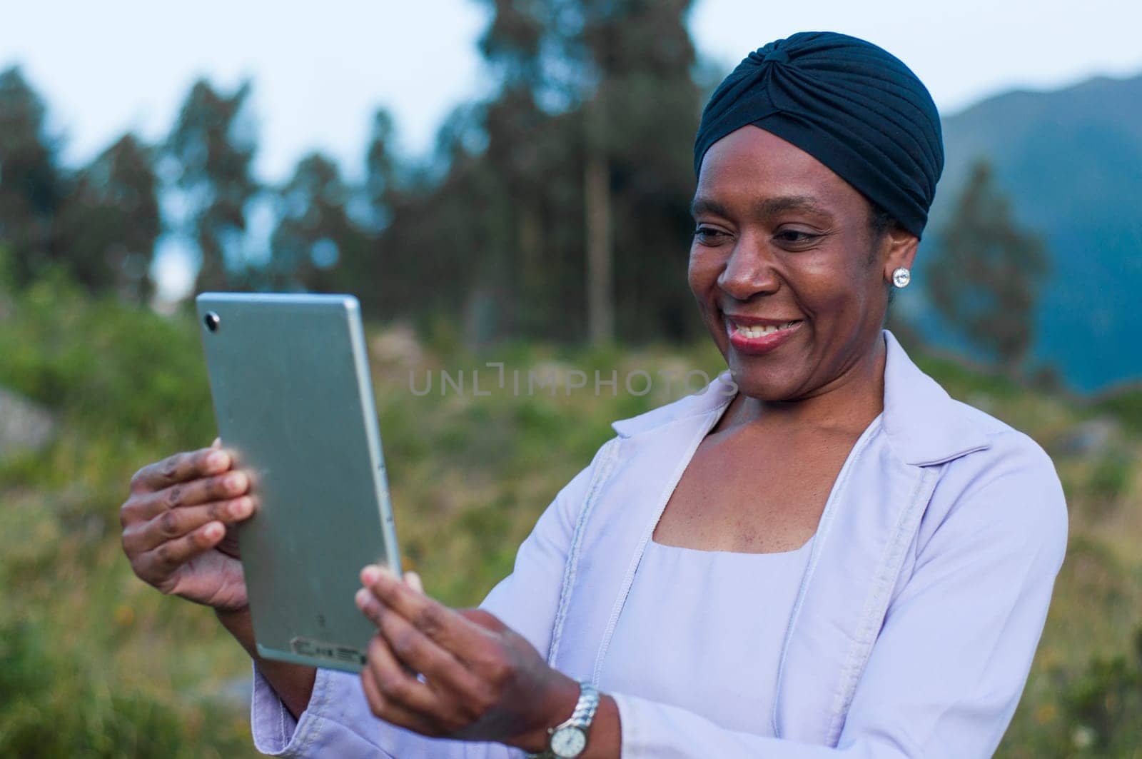 African businesswoman standing in nature with a tablet and smiling at camera happy and smiling. High quality photo