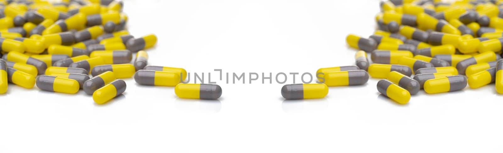 Yellow and gray probiotic capsule pill on white background. Probiotic supplement. Gut health. Dietary supplements. Probiotics for a healthy gut. Lactobacillus acidophilus and Bifidobacterium animalis.