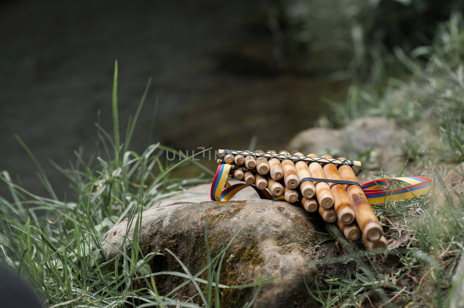 an andean flute of an indigenous person on top of a stone next to a river in the amazon of ecuador. High quality photo