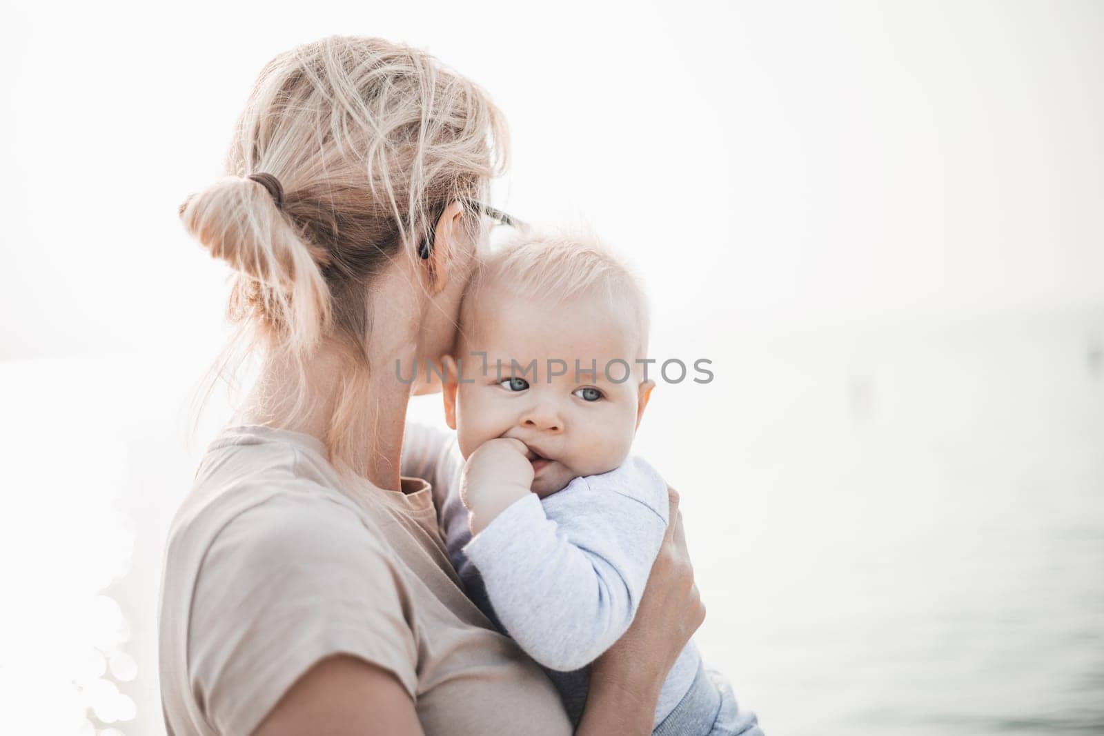 Tender woman caressing her little baby boy infant child outdoors. Mother's unconditional love for her child.