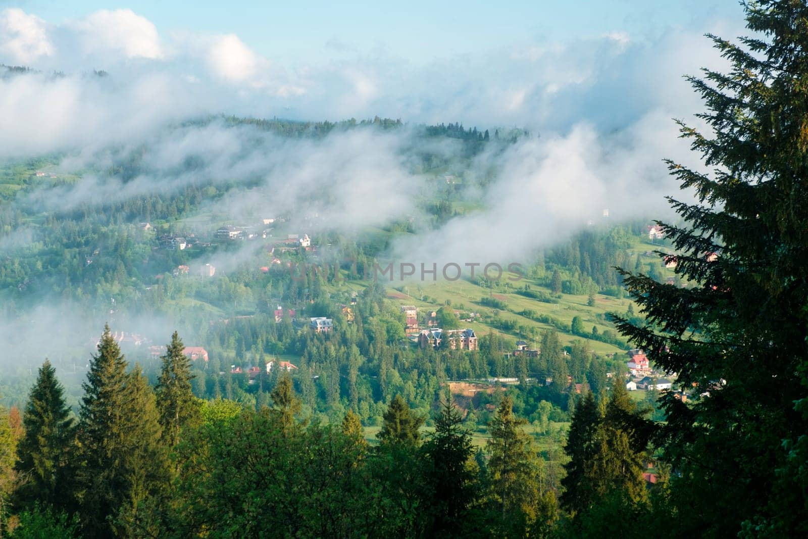 Aerial view village in mountain valley in fog. Morning fog on a hills of mountain village. Beautiful idyllic landscape. Carpathians, Ukraine, Europe. download photo