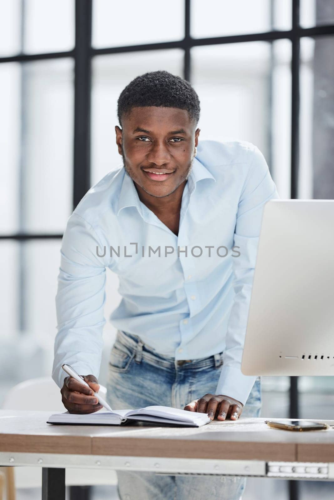 Serious thoughtful millennial businessman standing leaning on desk