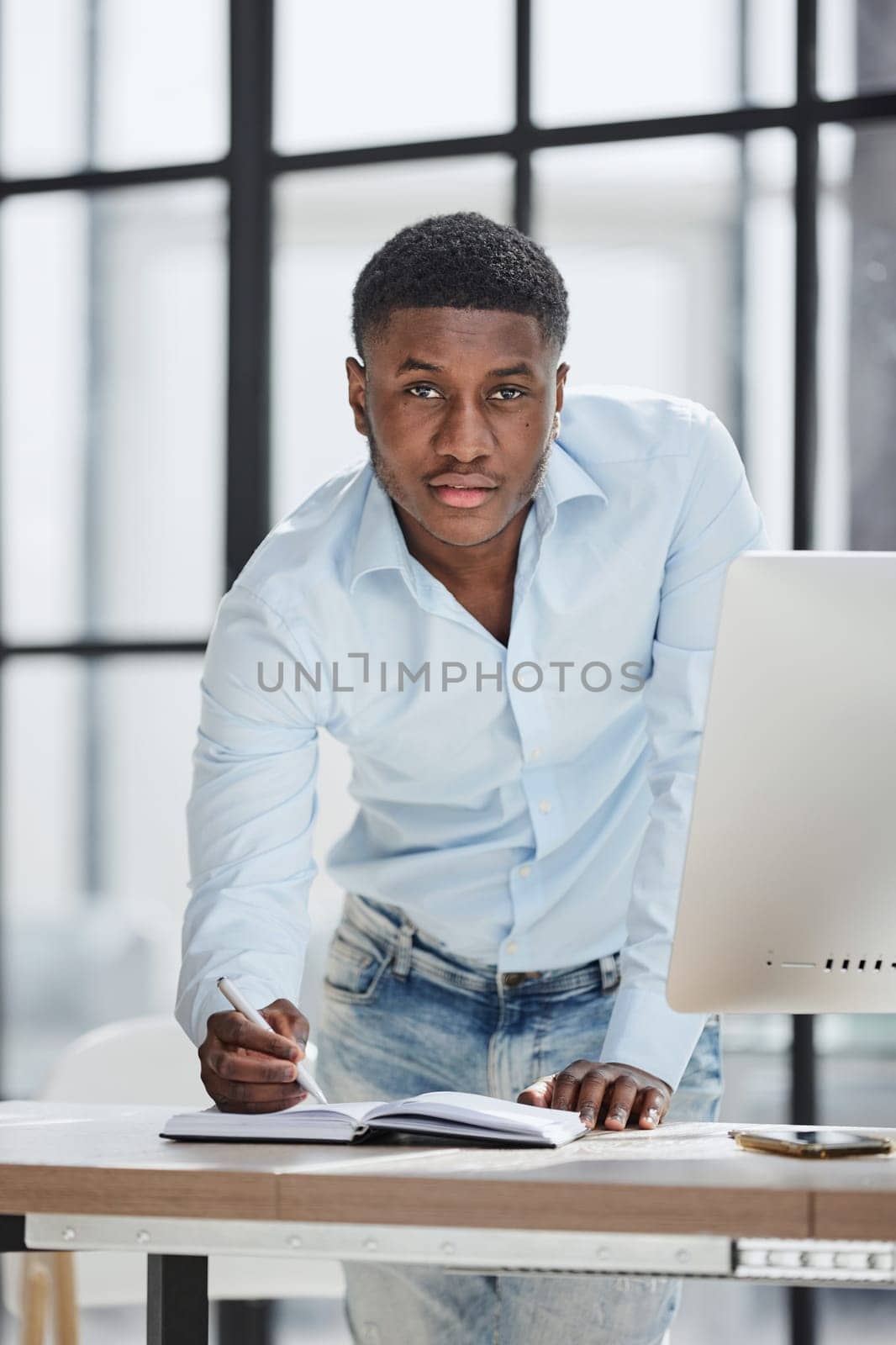 Serious thoughtful millennial businessman standing leaning on desk