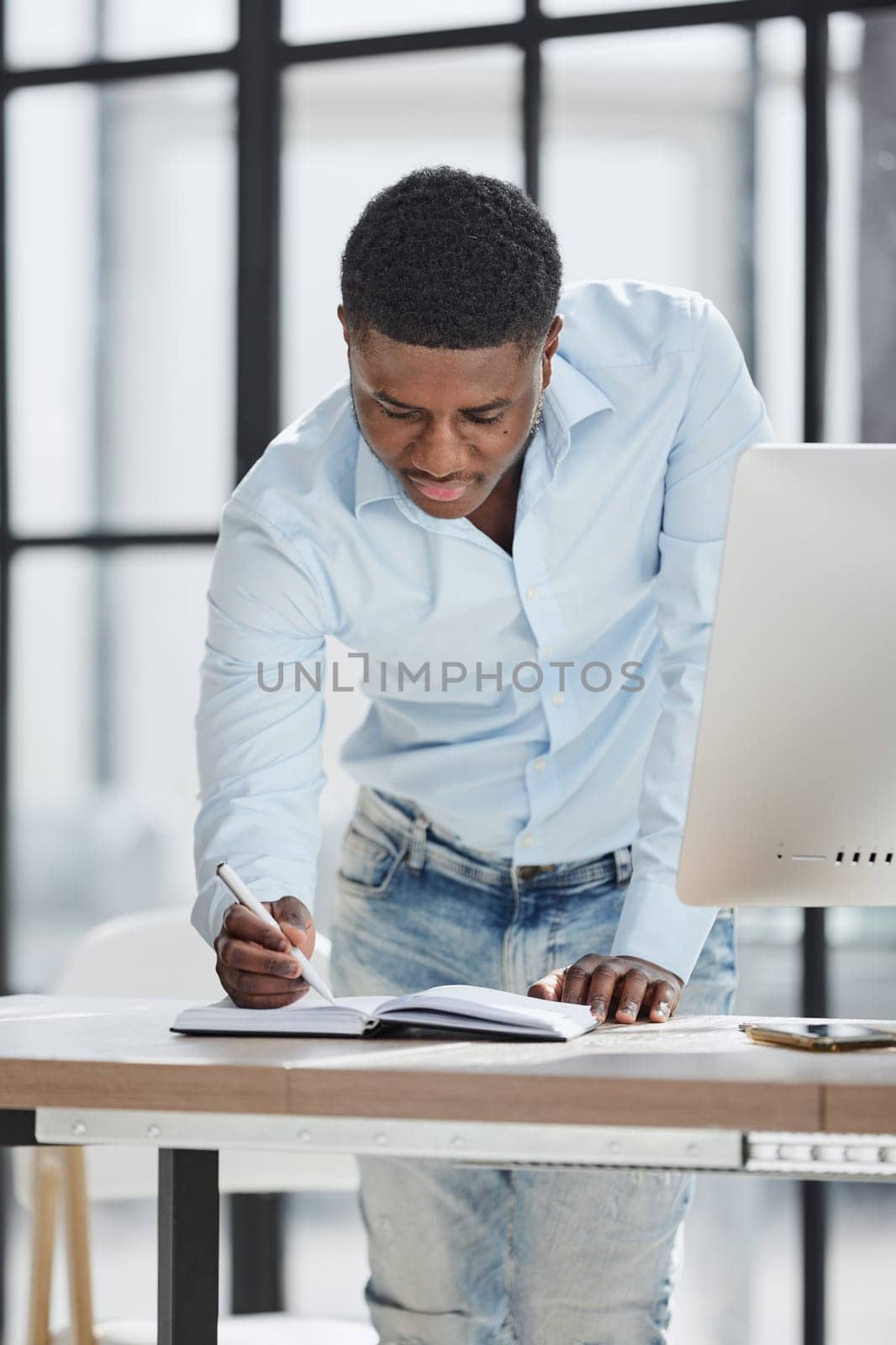 Serious thoughtful millennial businessman standing leaning on desk