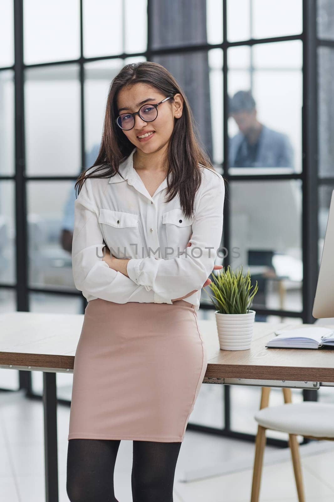 Smiling businesswoman standing at full height and looking at camera in an office by Prosto