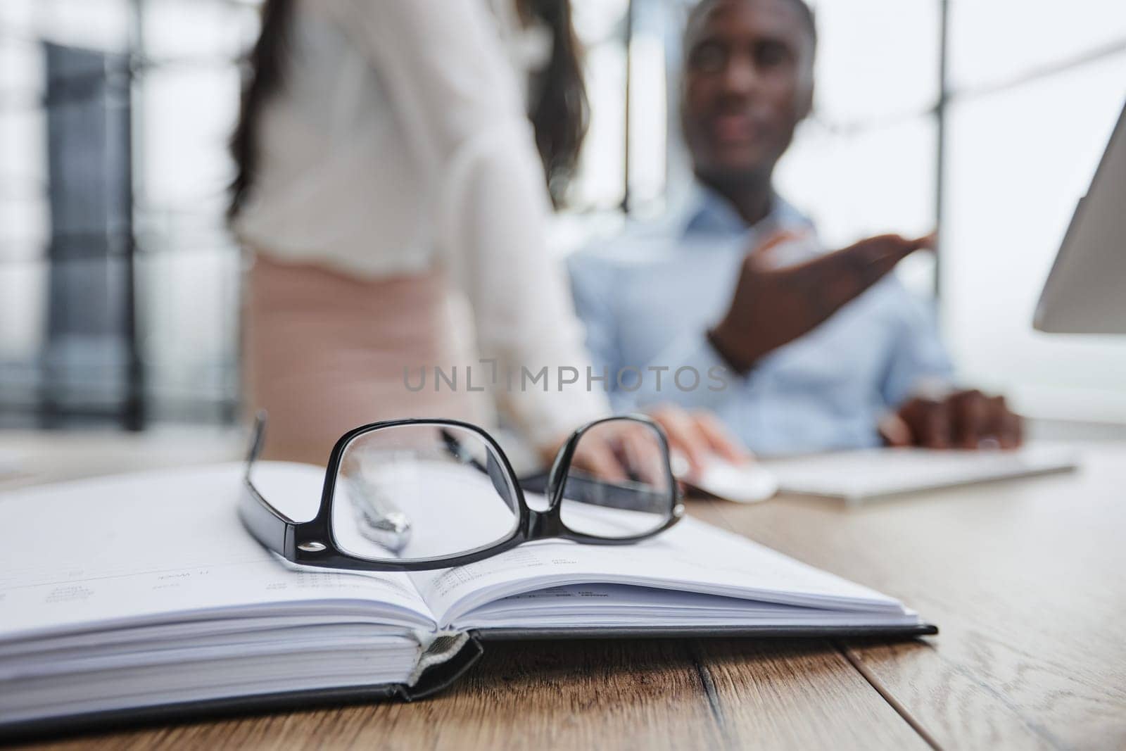 The glasses are on the work table. Against a blurred background, the guy works at a laptop