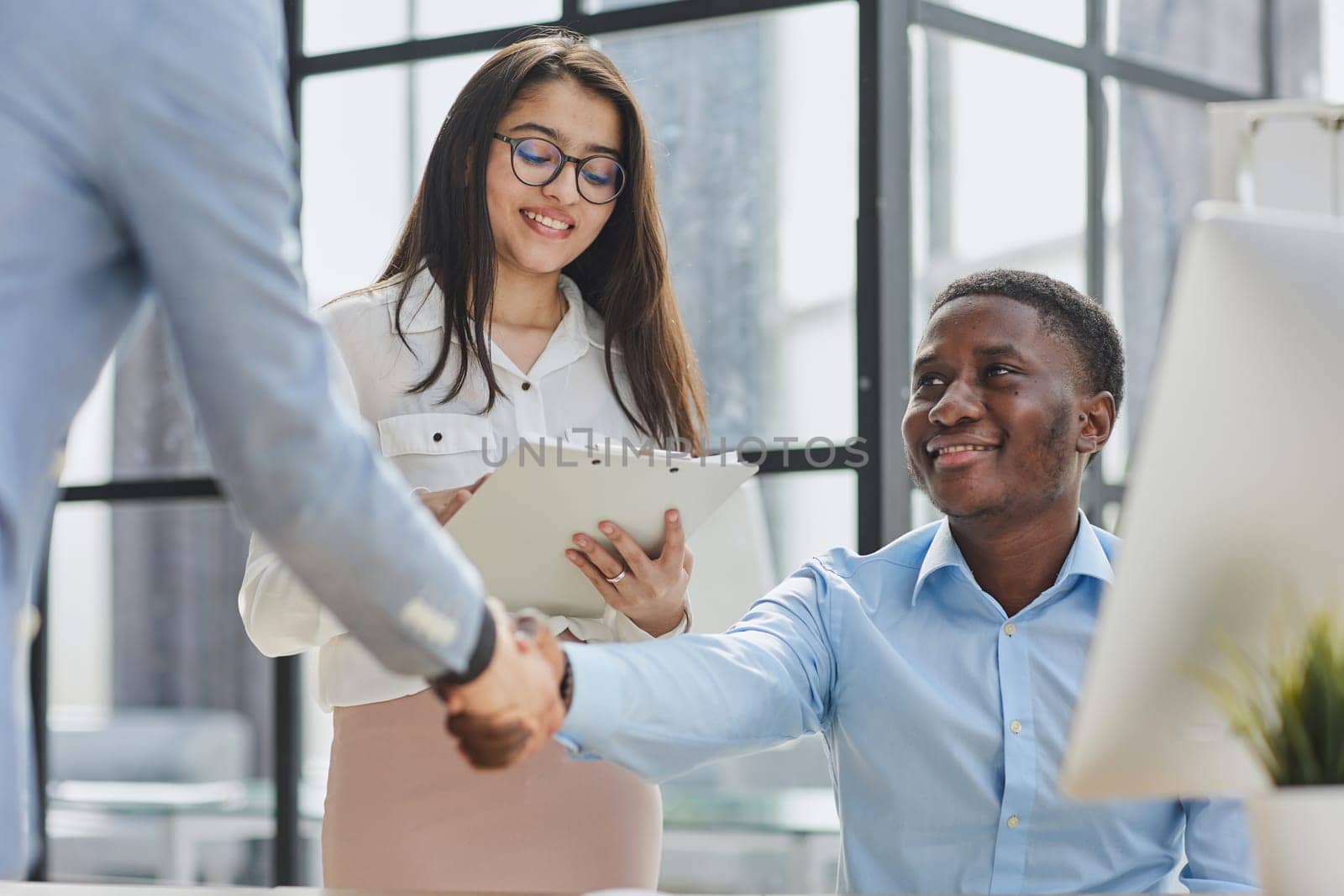 Cheerful multiracial colleagues discussing startup project and smiling during workday in office interior