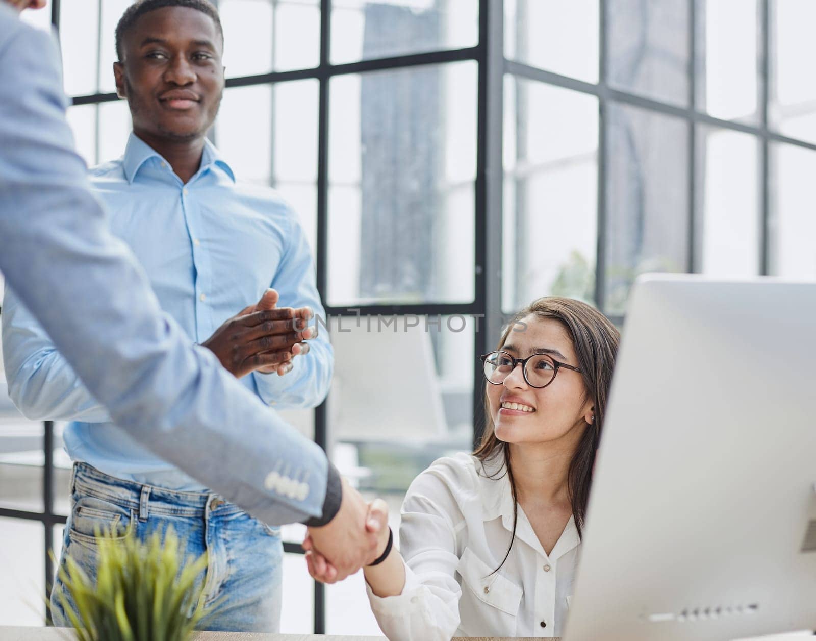 Cheerful multiracial colleagues discussing startup project and smiling during workday in office interior