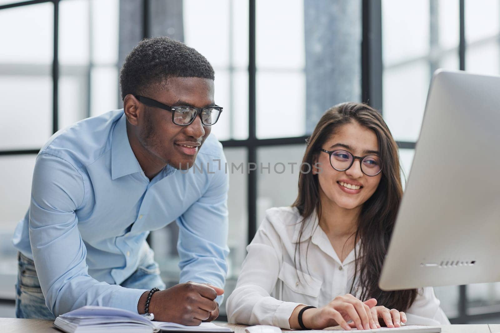 happy Middle Eastern and African American partners using laptop computer at table desktop