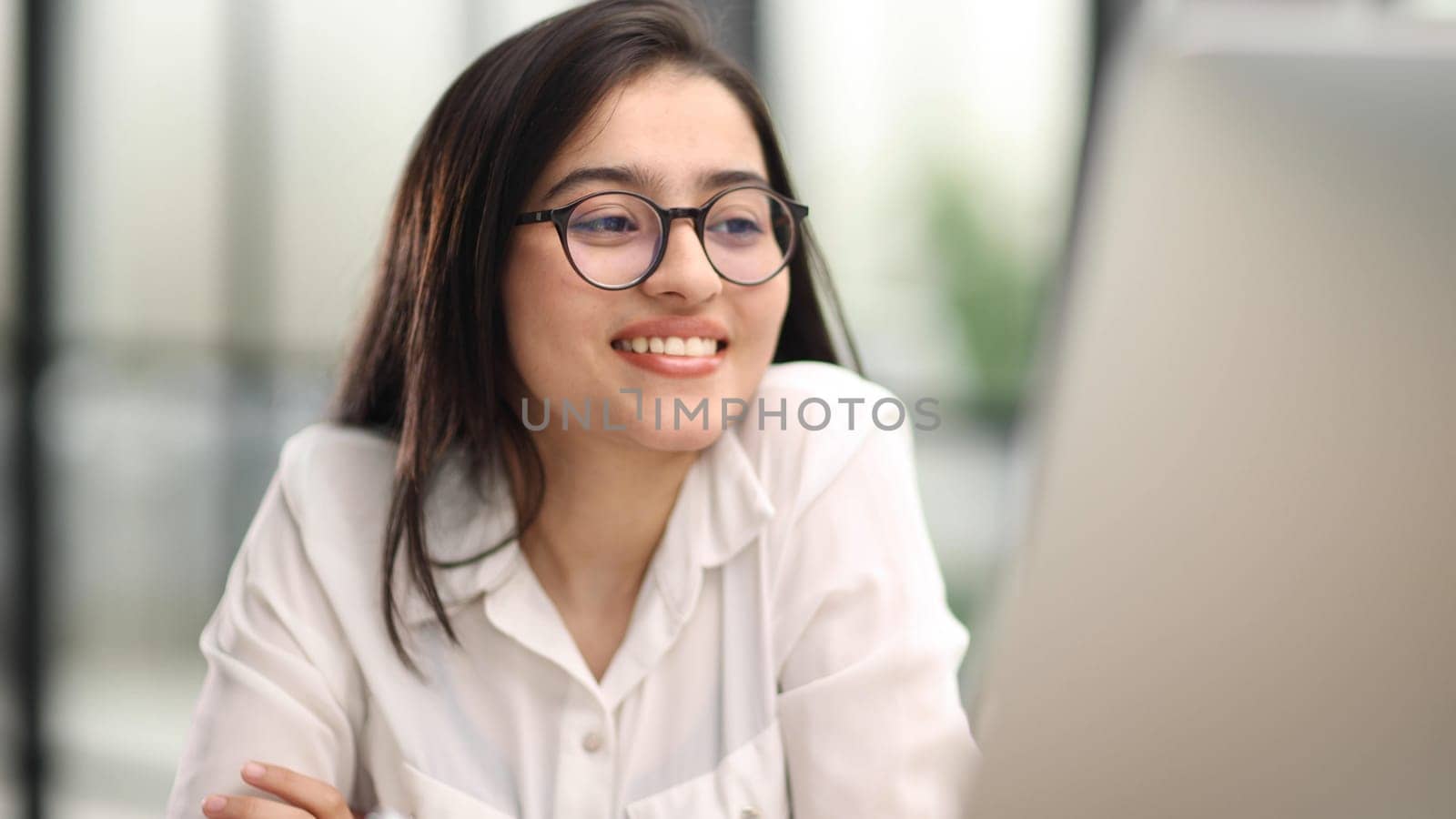 working on her computer or laptop at the office desk. Looking satisfied about her job and carrier.