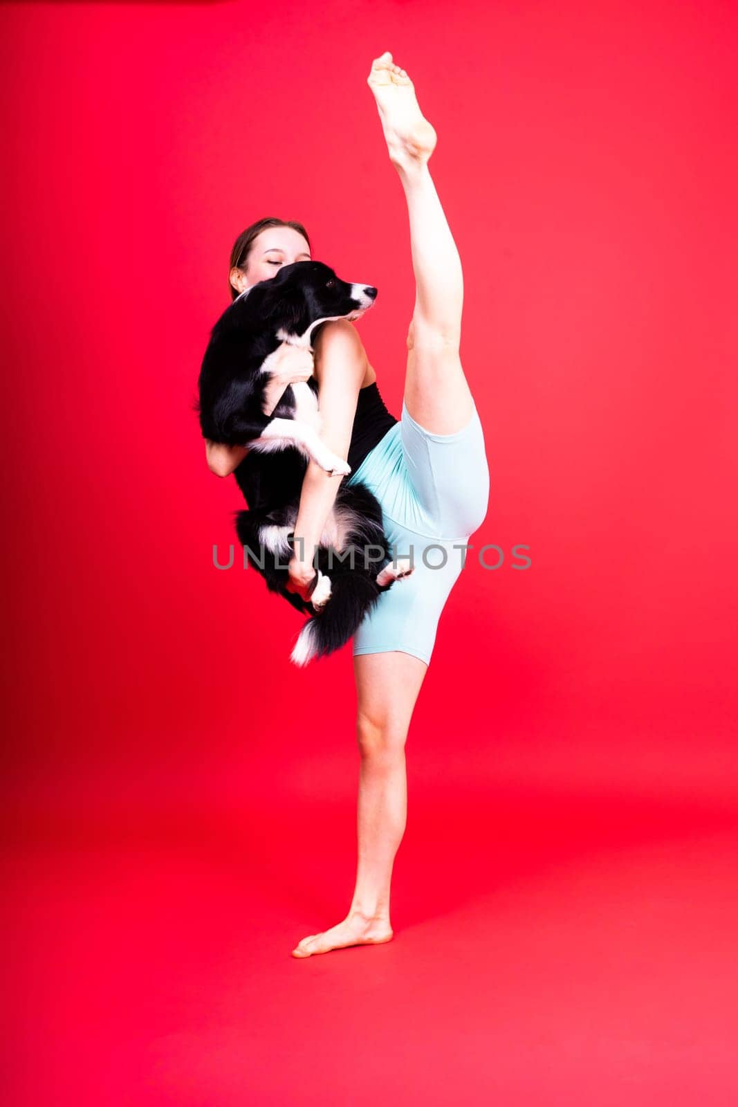 Excited girl dancing with border collie. Studio portrait lady looking at a dog with surprised smile.