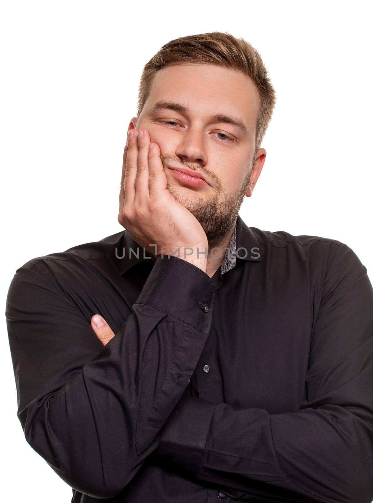 Studio portrait of gloomy european man showing boredom while leaning head on hand and standing over white background. by nazarovsergey