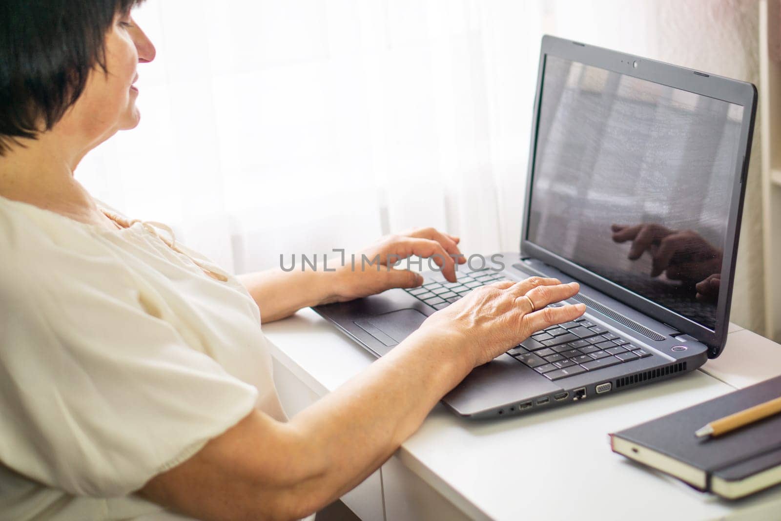 Senior business woman working at her computer laptop at home. Business, education and technology concept. Portrait of a skilled female programmer freelancer with laptop sitting on the table in an office.