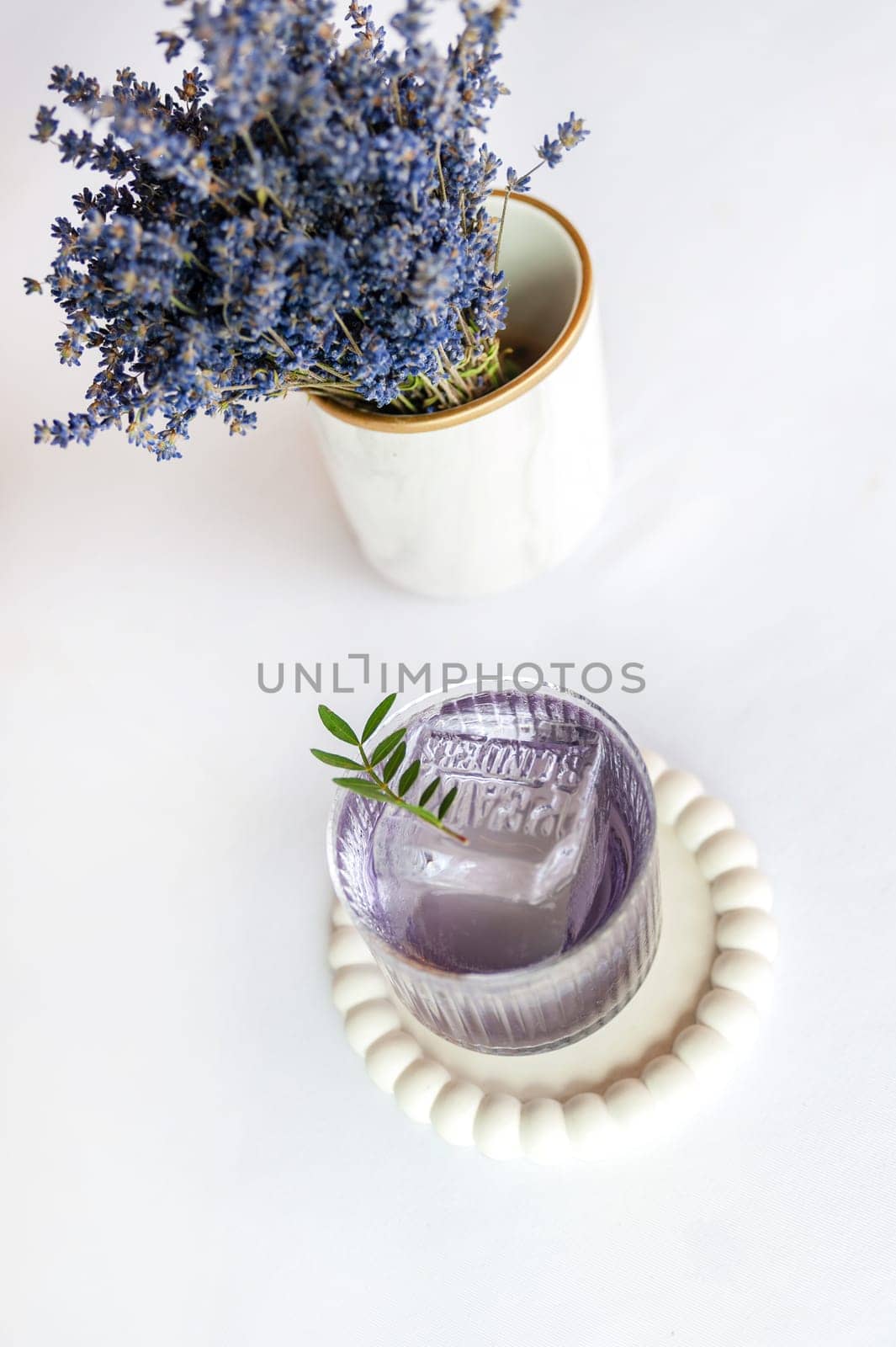 Lavender summer cocktail with ice in glass on the white table