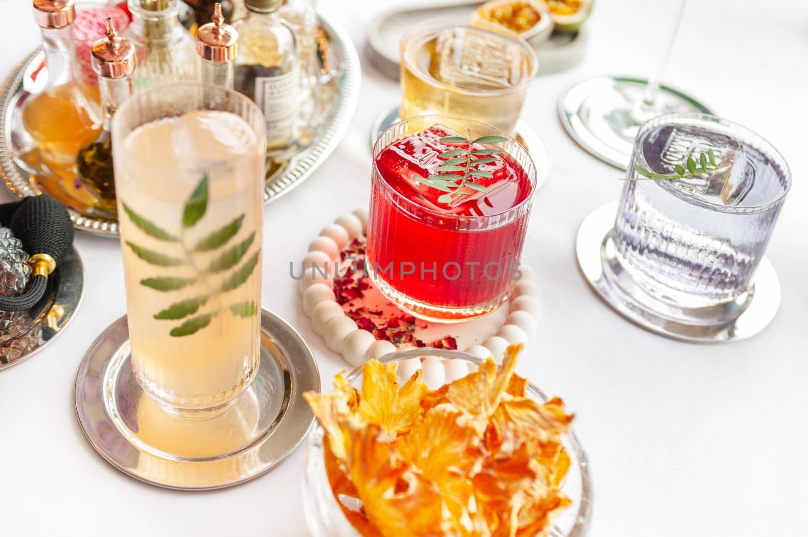 Five colorful summer cocktails in glasses on white table. Assortment of fresh summer drinks. Orange and red sangria cocktails, orange punch cocktail, margarita cocktail, tropical mule.