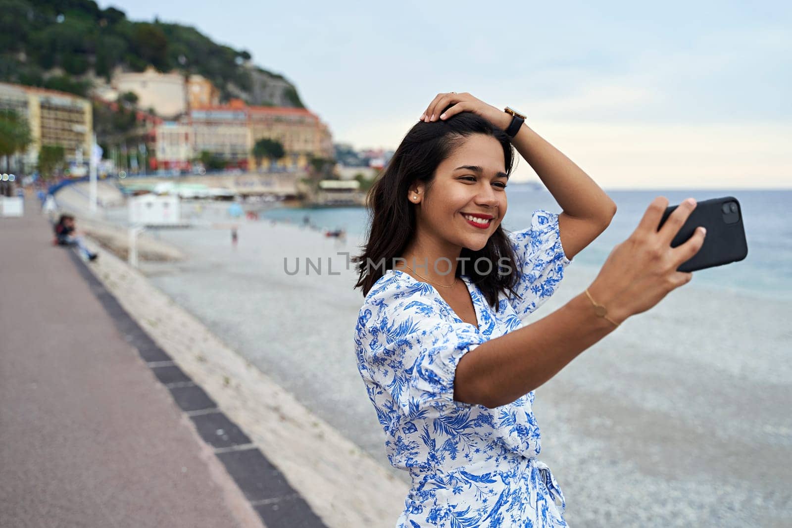 Beautiful smiling young woman takes selfie with a smartphone at the Promenade des Anglais in Nice, France