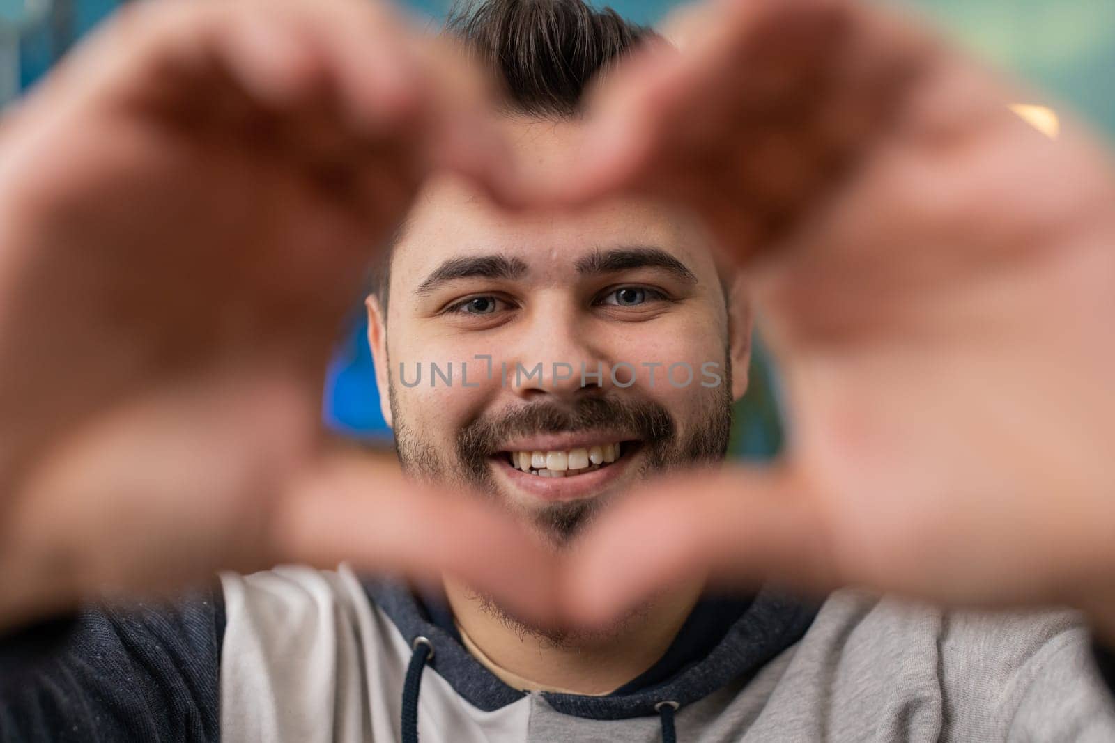 I love you. Happy Caucasian man at home living room couch makes symbol of love, showing heart sign to camera, express romantic feelings express sincere positive feelings. Charity, gratitude, donation