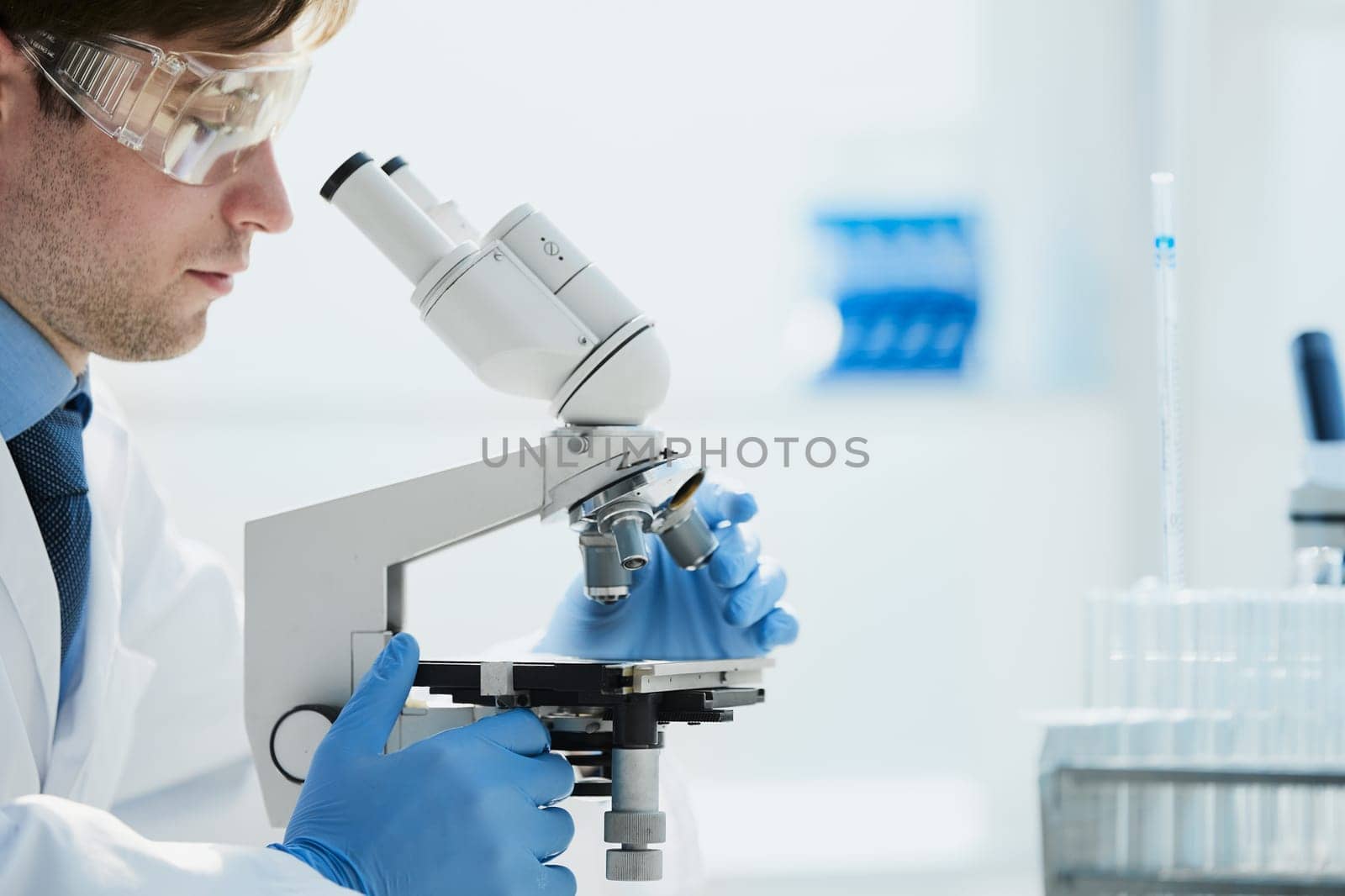 selective focus of male scientist looking through microscope in laboratory
