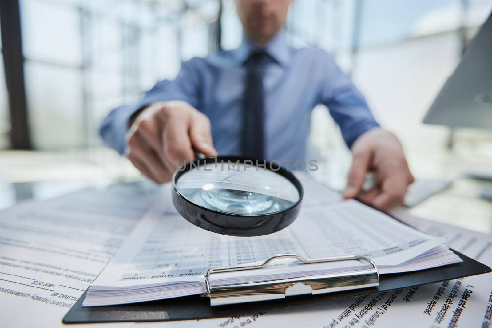 man looking through a magnifying glass to documents notebook.