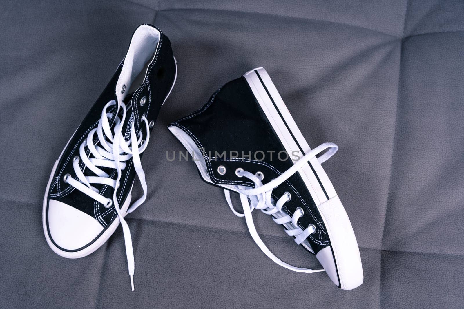 new youth sneakers with lacing lie on the home sofa. Trendy fashionable casual concept. High quality photo