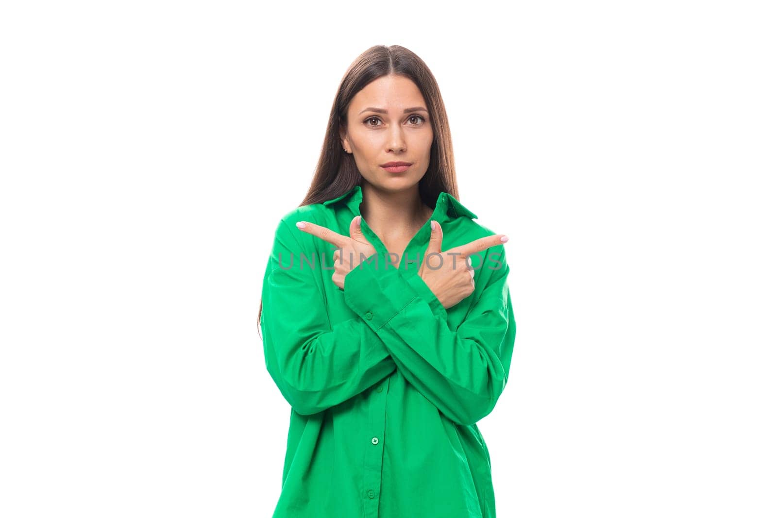 young european female model with well-groomed black hair and make-up dressed in a green shirt crossed her arms in front of her on a white background with copy space.
