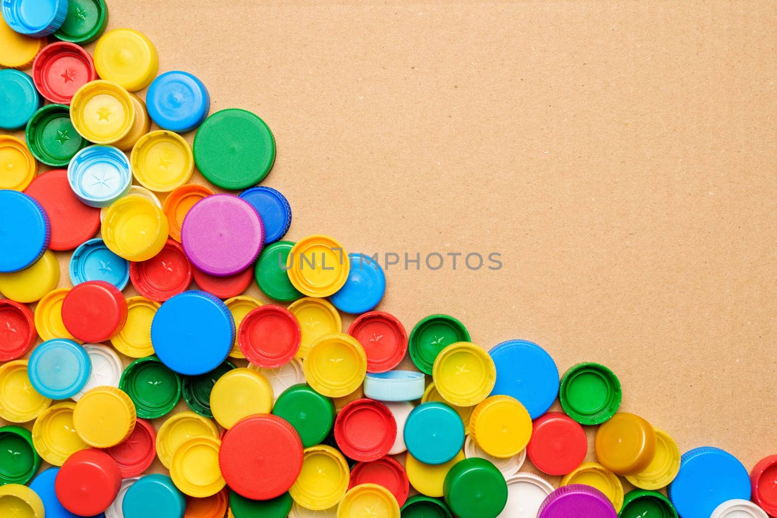 Used PET recycling plastic bottle cap plastic lids. Colorful bottle caps background cardboard box. Garbage PET waste recycling bottle cap sorting waste plastic garbage collection. Recyclable materials