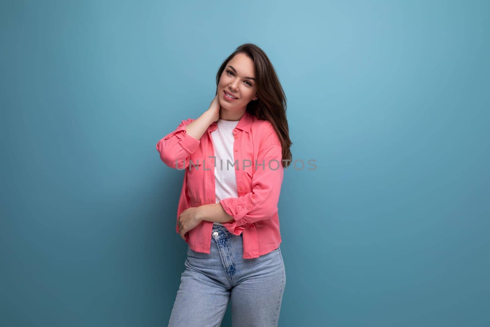 portrait of a woman with dark brown hair in jeans and a tank top with a shirt posing in the studio.