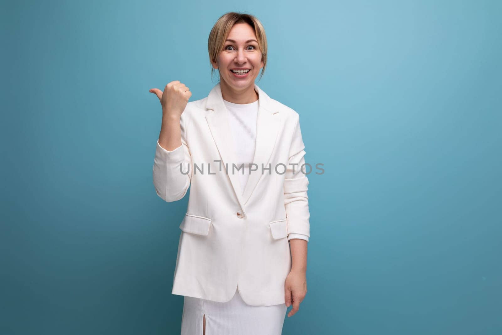 pretty slender young blond business leader woman in a white jacket points her finger towards the wall with inspiration.