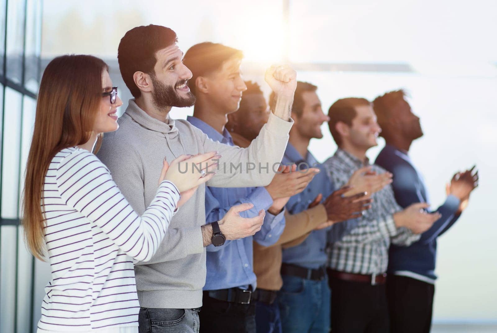 Applause. Group of cheerful young multi-ethnic people standing in a row and applauding to someone while standing
