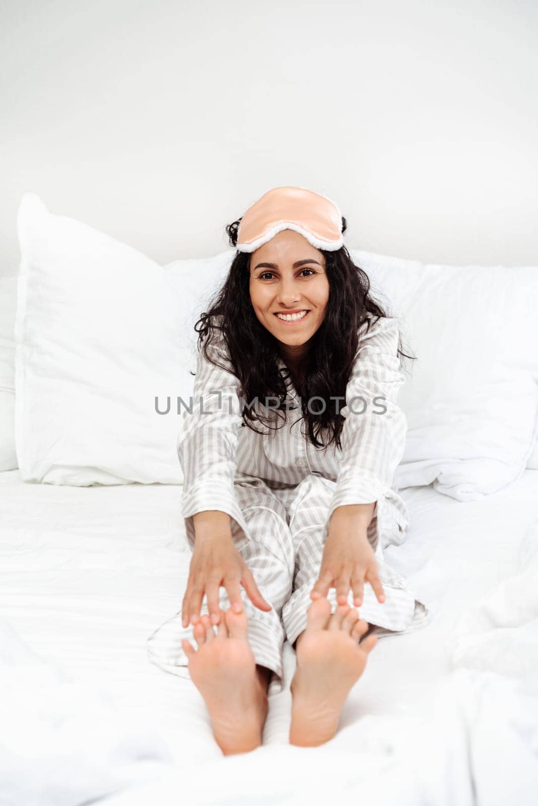 Young Hispanic woman waking up doing exercises. The girl in a pleasant atmosphere enjoys the morning rituals. The hands reach for the feet, she succeeds and this gives her strength and energy